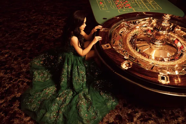 A woman in a luxurious green gown next to an ornate roulette wheel, capturing the upscale casino mood of LUCK789.
