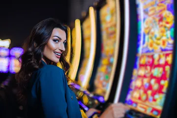 A woman smiling by bright slot machines showing lucky symbols, showcasing the exciting slot offerings at LUCK789.
